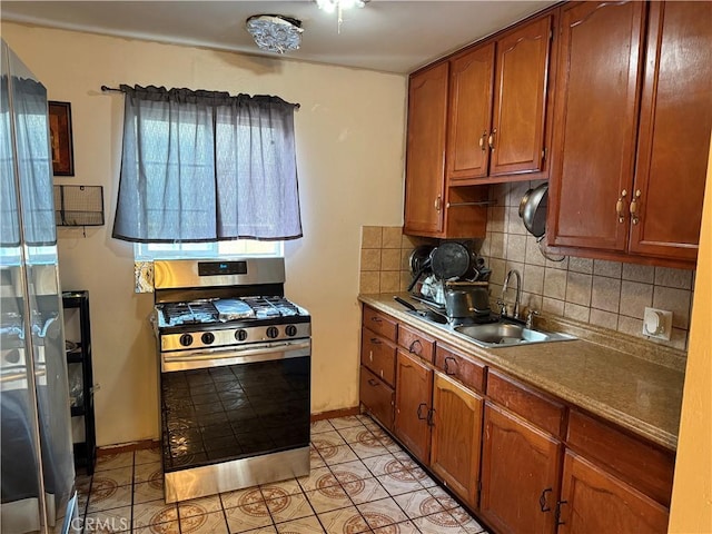 kitchen with stainless steel range with gas cooktop, sink, light tile patterned floors, and decorative backsplash