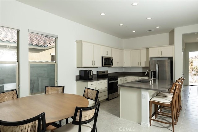 kitchen featuring sink, white cabinetry, appliances with stainless steel finishes, a kitchen breakfast bar, and a kitchen island with sink