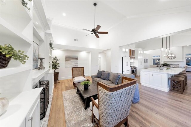 living room with light hardwood / wood-style flooring, high vaulted ceiling, and ceiling fan with notable chandelier