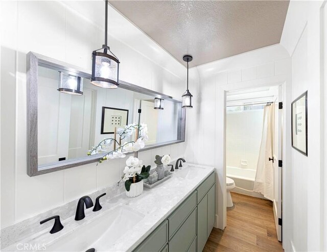 full bathroom with a textured ceiling, hardwood / wood-style flooring, toilet, shower / bath combo, and vanity