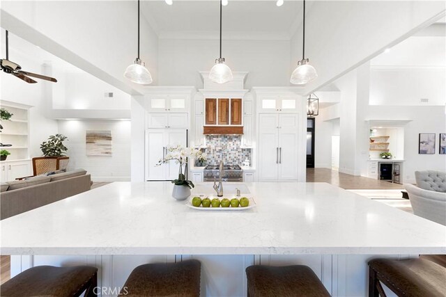 kitchen featuring a large island with sink, a breakfast bar area, white cabinetry, and hanging light fixtures