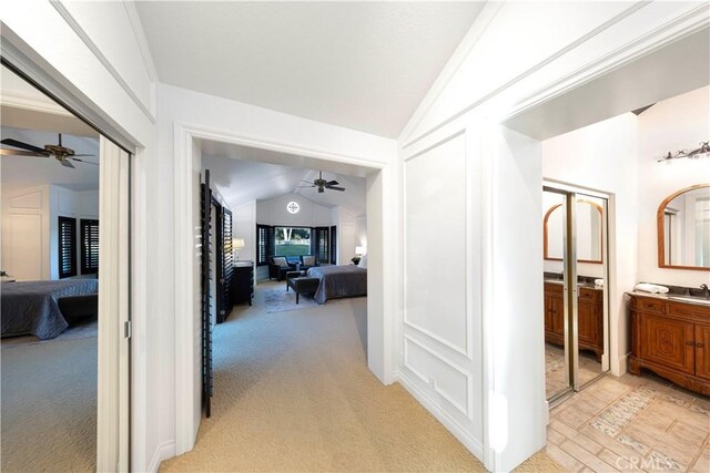 hallway featuring sink, light colored carpet, lofted ceiling, and crown molding