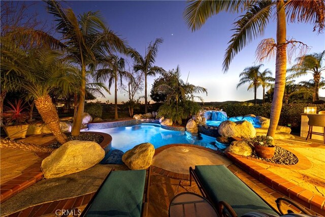 pool at dusk featuring a patio