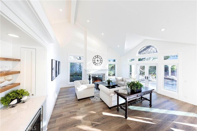 living room featuring beverage cooler, dark hardwood / wood-style flooring, french doors, high vaulted ceiling, and a fireplace