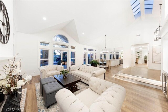 living room featuring high vaulted ceiling, a notable chandelier, and light hardwood / wood-style flooring