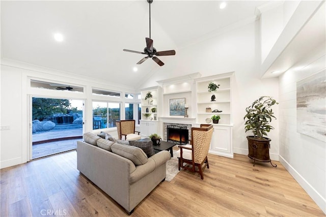 living room featuring light hardwood / wood-style floors, ceiling fan, a fireplace, and built in shelves