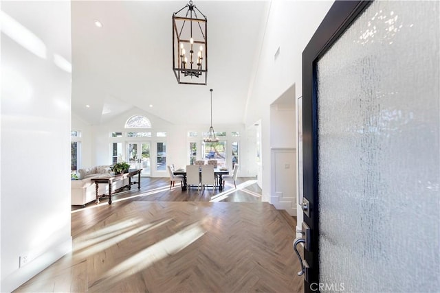 entrance foyer with a high ceiling, a notable chandelier, french doors, and parquet flooring