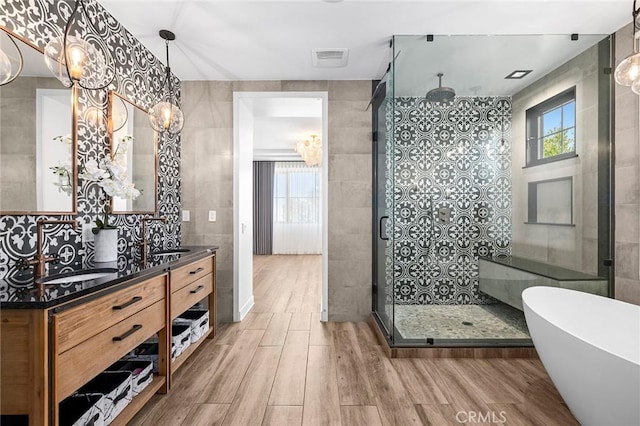 bathroom with vanity, tile walls, a healthy amount of sunlight, and plus walk in shower