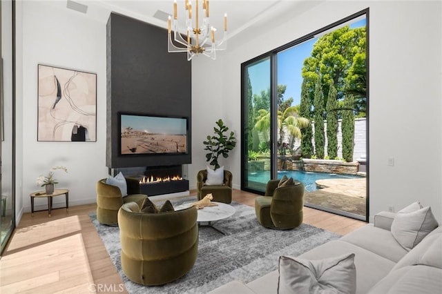 living room with hardwood / wood-style floors, an inviting chandelier, and a large fireplace