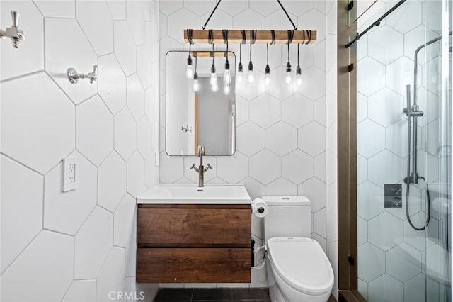 bathroom with tile walls, vanity, a shower with shower door, and toilet