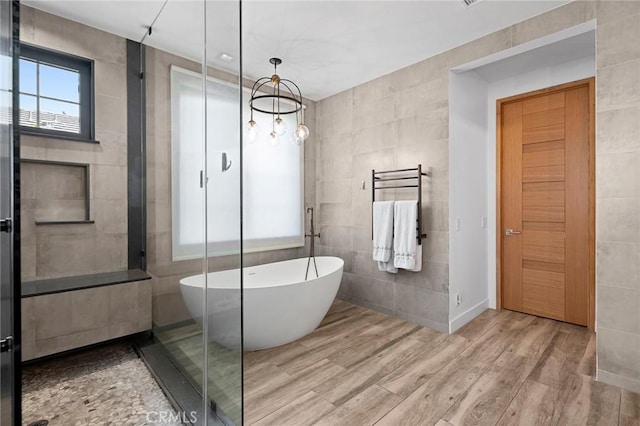 bathroom with a washtub, tile walls, and hardwood / wood-style floors