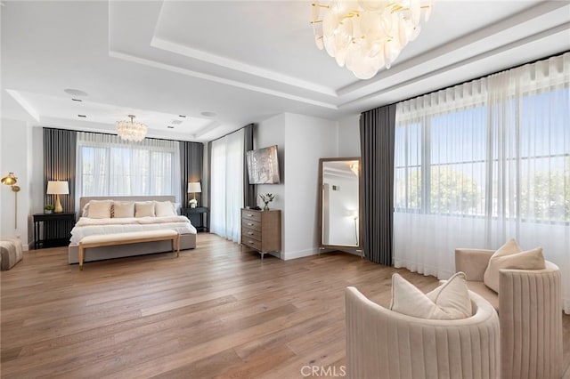 bedroom featuring a raised ceiling, hardwood / wood-style flooring, and a notable chandelier