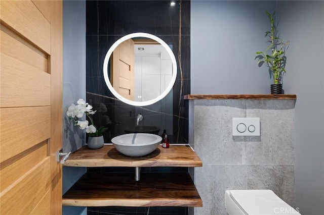 bathroom with tile walls, sink, and toilet