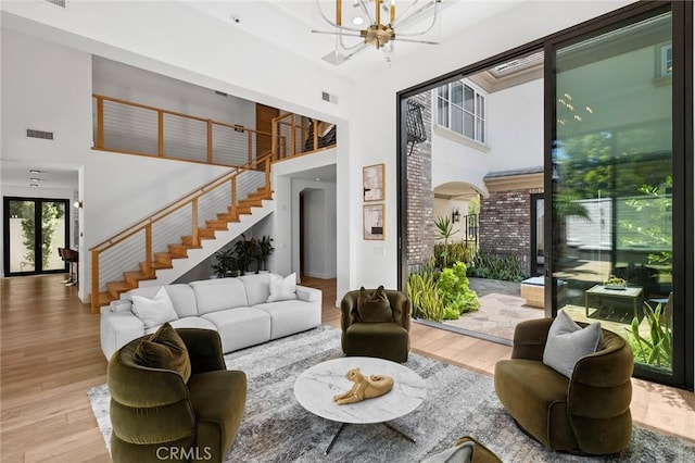 living room featuring a towering ceiling, a notable chandelier, and light hardwood / wood-style floors