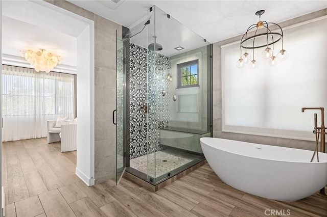 bathroom featuring shower with separate bathtub, wood-type flooring, and a notable chandelier