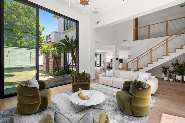 living room featuring a towering ceiling, light wood-type flooring, and ceiling fan