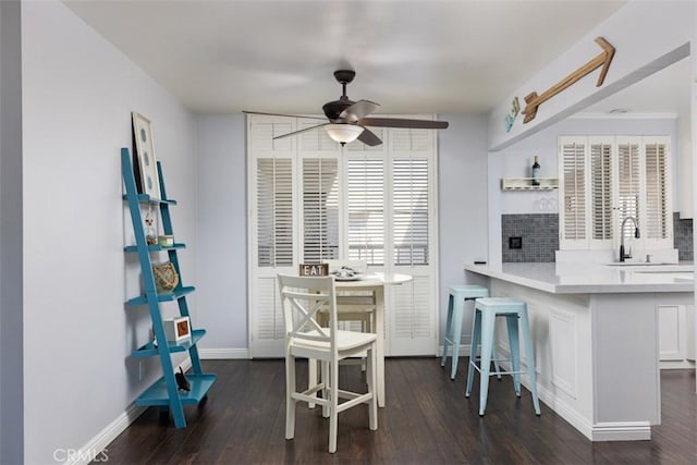 dining area with sink, ceiling fan, and dark wood-type flooring