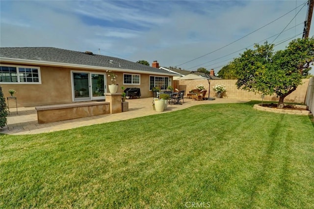 rear view of house with a patio and a lawn