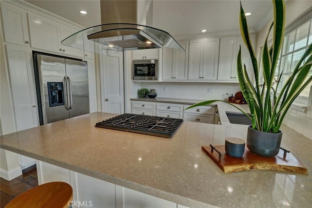 kitchen with island exhaust hood, appliances with stainless steel finishes, light stone countertops, and white cabinets