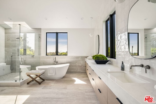 bathroom with vanity, tile walls, independent shower and bath, and plenty of natural light