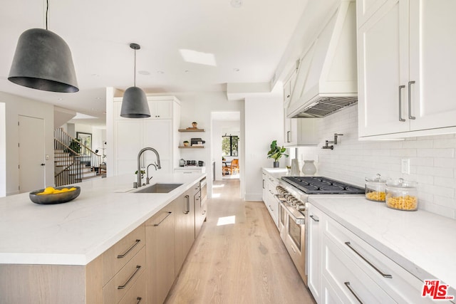 kitchen with sink, custom exhaust hood, double oven range, and hanging light fixtures