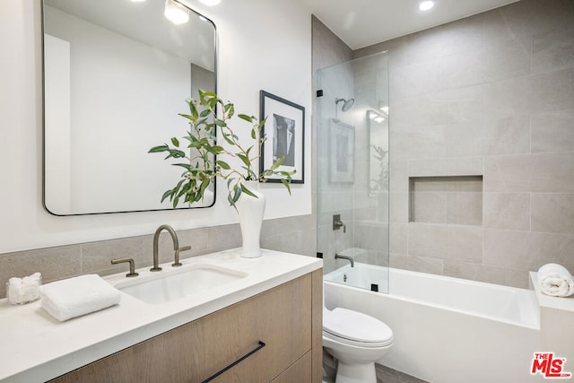 full bathroom featuring toilet, tiled shower / bath, and vanity