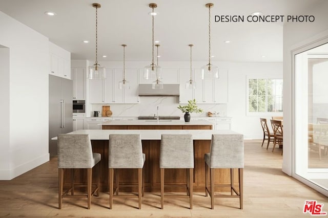 kitchen featuring stainless steel appliances, white cabinetry, tasteful backsplash, and an island with sink