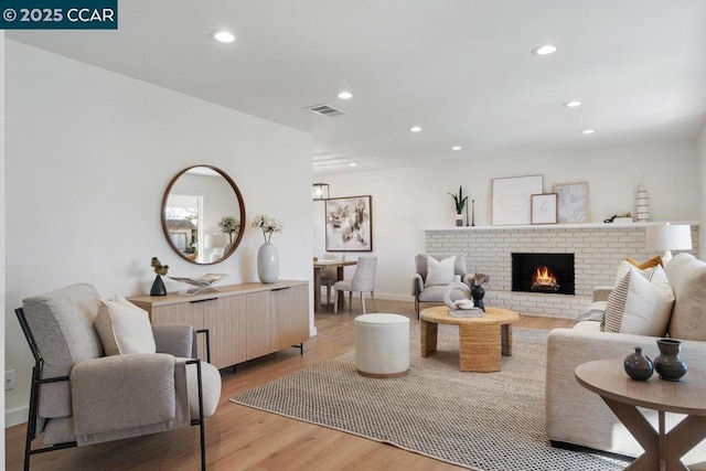 living room with a brick fireplace and light hardwood / wood-style floors