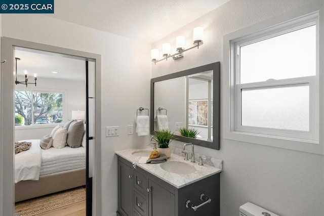 bathroom with hardwood / wood-style flooring, an inviting chandelier, and vanity