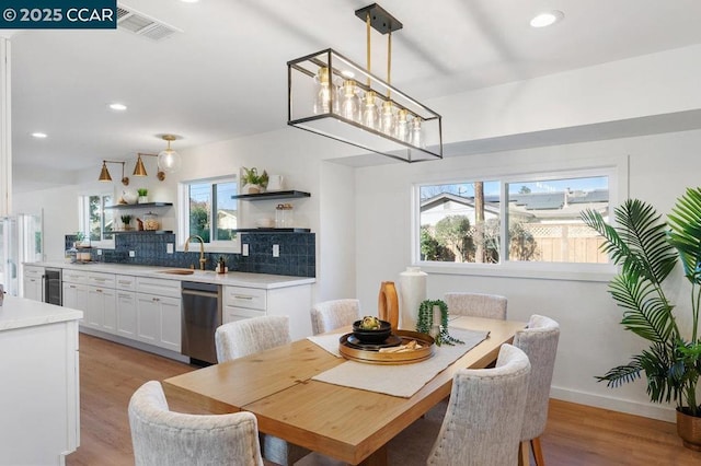 dining space featuring sink, light hardwood / wood-style flooring, beverage cooler, and a chandelier