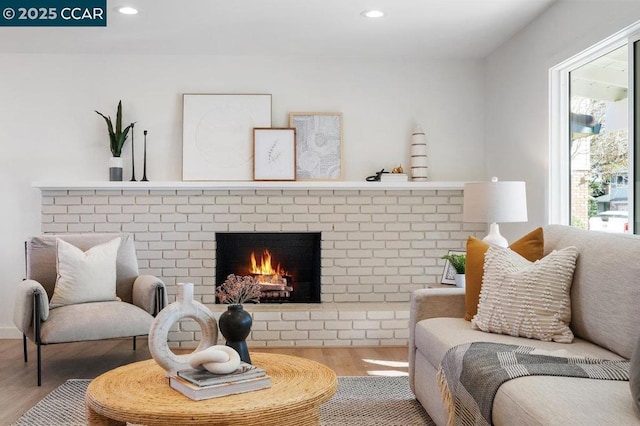 living room with hardwood / wood-style flooring, a brick fireplace, and plenty of natural light