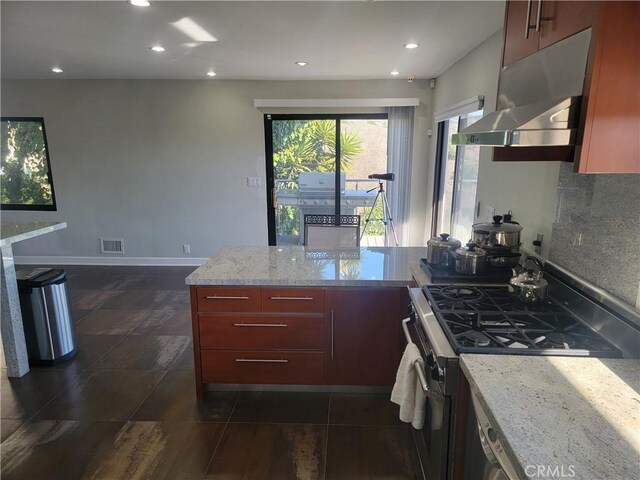 kitchen featuring tasteful backsplash, visible vents, a peninsula, under cabinet range hood, and stainless steel range with gas stovetop