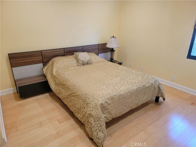 bedroom with baseboards and light wood finished floors