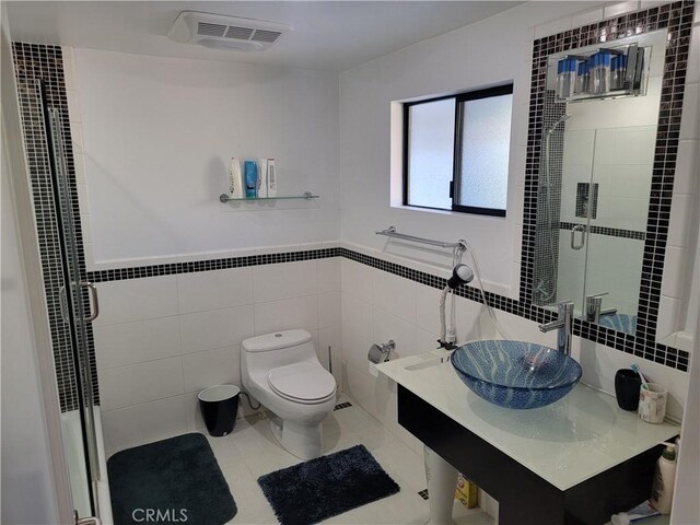 bathroom with a shower stall, a sink, visible vents, and tile walls