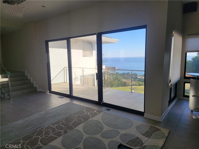 entryway with a water view, tile patterned flooring, visible vents, and baseboards