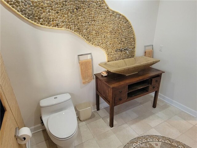 bathroom with a sink, toilet, and baseboards