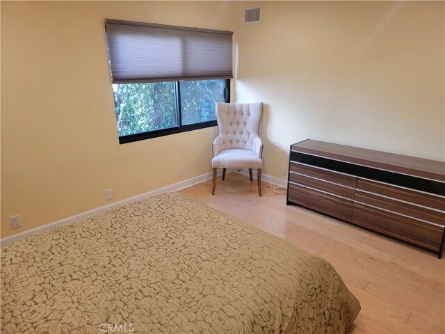 bedroom featuring wood finished floors, visible vents, and baseboards