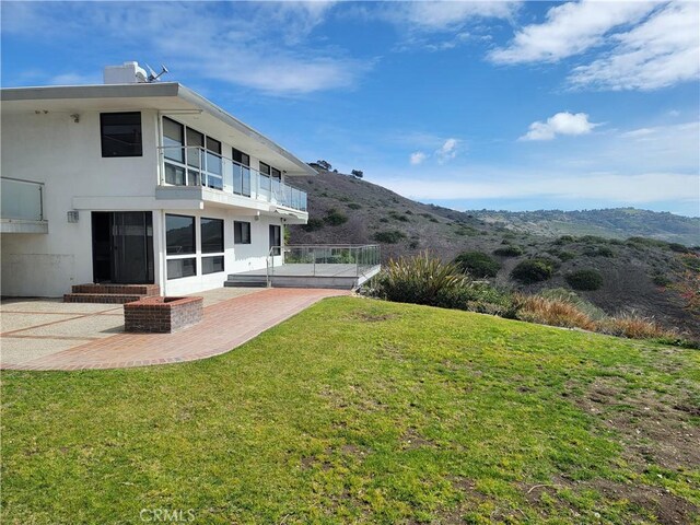 view of yard featuring a patio area, a mountain view, and a balcony