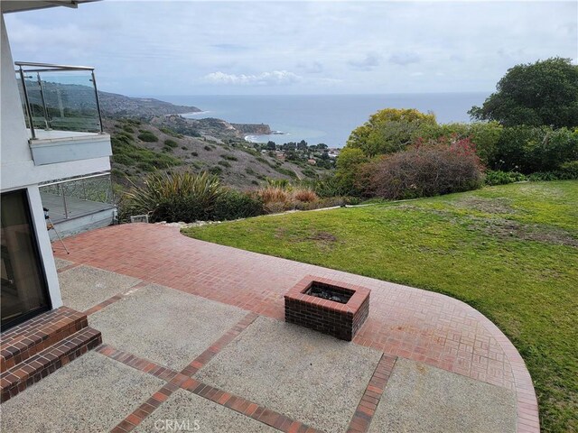 exterior space featuring a patio, an outdoor fire pit, a lawn, and a water view