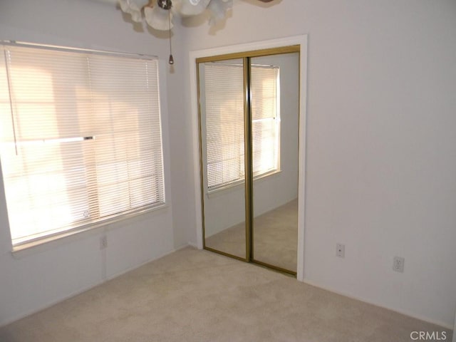 unfurnished bedroom with ceiling fan, a closet, and light carpet