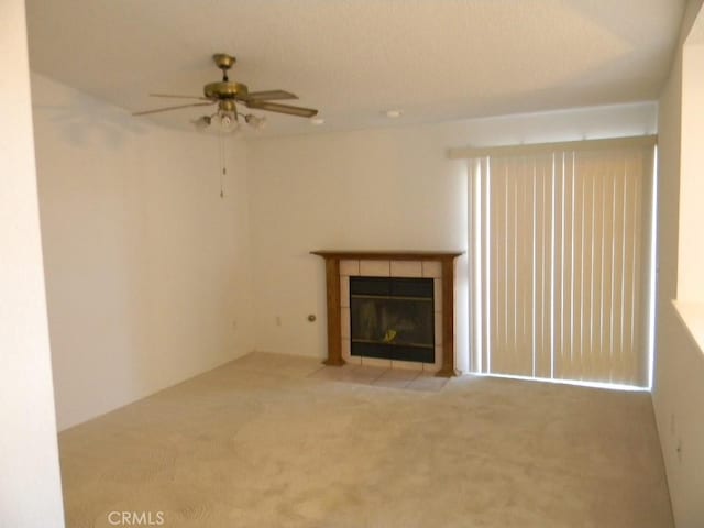 unfurnished living room with a fireplace, ceiling fan, and carpet