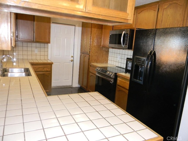 kitchen featuring black appliances, tasteful backsplash, tile countertops, and sink