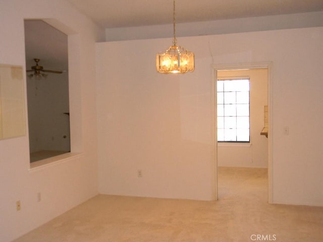 empty room featuring ceiling fan with notable chandelier and carpet