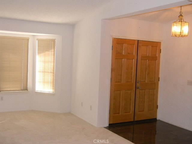 carpeted spare room with a notable chandelier