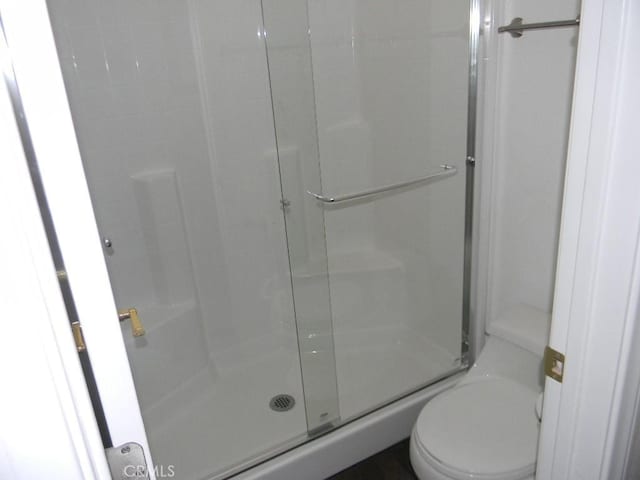 bathroom featuring toilet and an enclosed shower