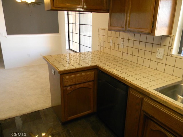 kitchen with kitchen peninsula, tile counters, decorative backsplash, dark colored carpet, and black dishwasher