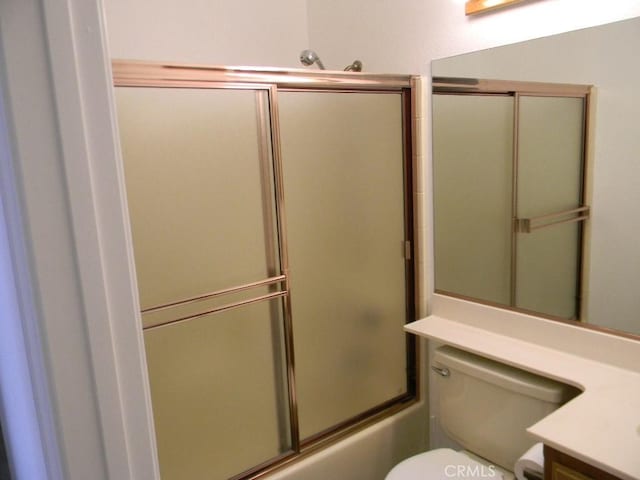 full bathroom featuring toilet, vanity, and bath / shower combo with glass door