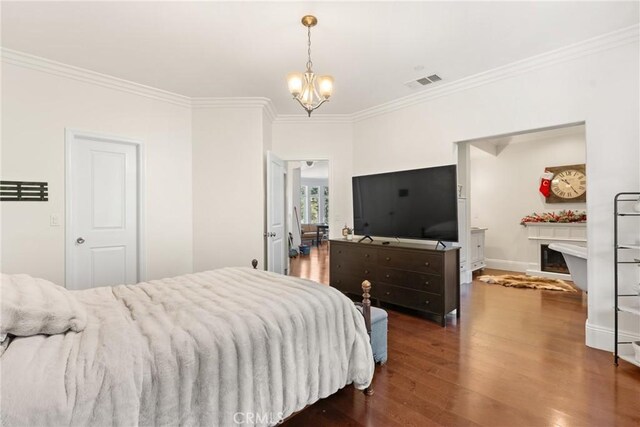 bedroom featuring crown molding, a fireplace, dark hardwood / wood-style flooring, and a notable chandelier