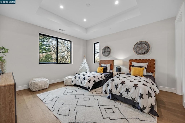 bedroom featuring a tray ceiling and light hardwood / wood-style flooring