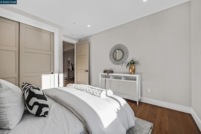 bedroom with dark hardwood / wood-style flooring and a closet